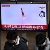 A man watches a television screen showing a news broadcast with file footage of a North Korean missile test, at a railway station in Seoul on December 31, 2022