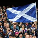 A Scotland fan waves a national flag as they enjoy the pre-match atmosphere prior to a Six Nations Rugby match at Murrayfield Stadium