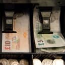 An open cash register containing pound coins and notes is pictured in a convenience store in London