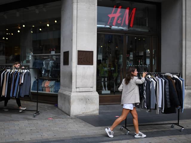 Retail workers move rails of clothes past a H&M store on Oxford Street.