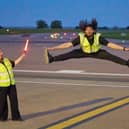 Airport ground handlers perform lively dance routine on runway.