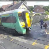 Shocking CCTV films the moment a girl risks her life at a level crossing, walking just a couples of metres in front of an advancing train.