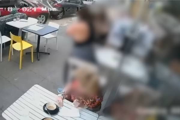 Two cars crash onto pavement narrowly missing café customers.