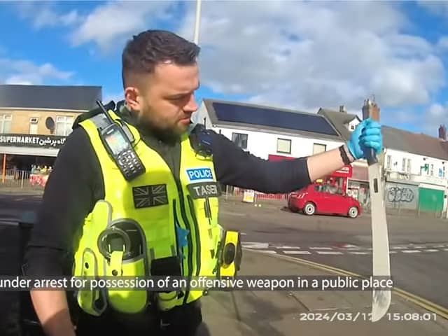 Police officer pulls huge machete from dealer's coat.