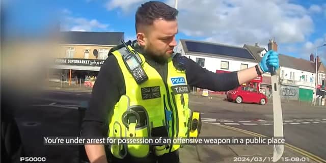Police officer pulls huge machete from dealer's coat.