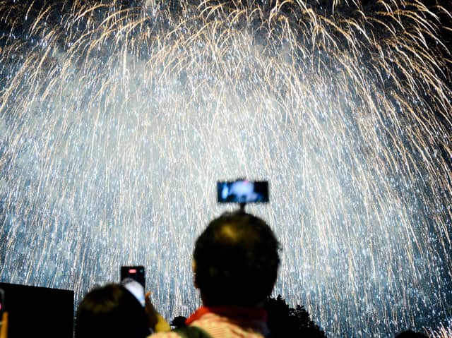 Person taking photo of a firework display. Photo: ANTHONY WALLACE/AFP via Getty Images