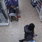 Video grab of Nicolae Boia crouched behind a trolley and filling his bag with unpaid for goods.