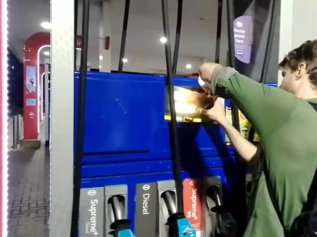Dr Patrick Hart cracks the display panels of petrol pumps at Esso Thurrock Services on the M25 on August 24 2022. 