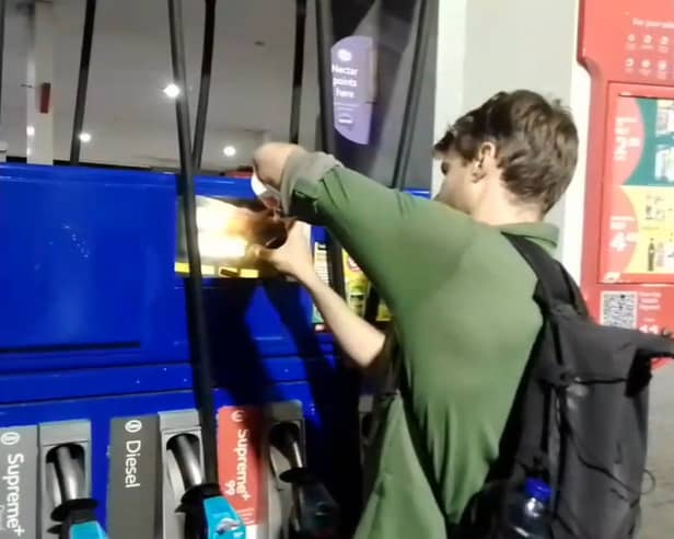 Dr Patrick Hart cracks the display panels of petrol pumps at Esso Thurrock Services on the M25 on August 24 2022. 