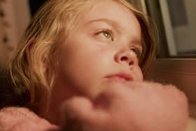 A child looking out of a window while she waits