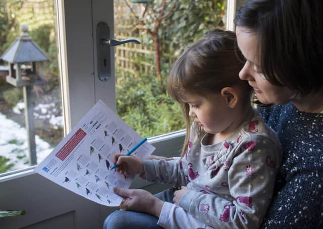 A mother and her daughter counting birds in their garden for the RSPB Big Garden Birdwatch. Photo: Eleanor Bentall.