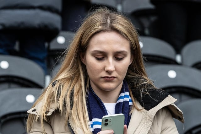 A PNE fan checks her phone at the MKM Stadium