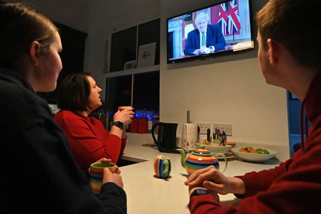 A family gather around the television to watch Britain's Prime Minister Boris Johnson give a televised message to the nation from 10 Downing Street in London (Photo by PAUL ELLIS/AFP via Getty Images)