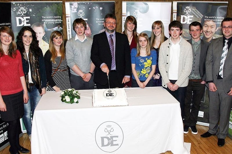Councillor Barry Lewis, Derbyshire County Council’s Cabinet Member for Young People, cuts the commemorative cake watched by Duke of Edinburgh Gold Award recipients including High Peak students. Photo contributed.