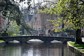 A woman walks with a dog across a bridge in the Cotswolds. (Photo by JUSTIN TALLIS/AFP via Getty Images)