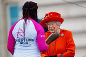 The Queen passes her baton to the baton bearer, British parasport athlete Kadeena Cox, during the launch of the Queen's Baton Relay for Birmingham 2022. (Photo by Victoria Jones - WPA Pool/Getty Images)