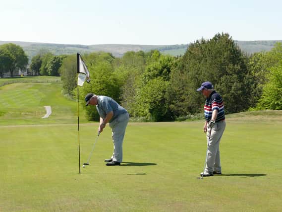 Long time member Barry Ashmore sinks a putt on the 15th Hole as Mike Gardiner watches on.