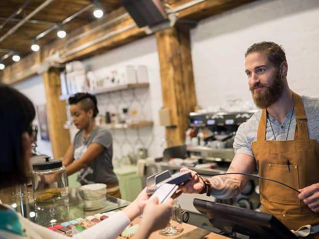 Customer paying barista with credit card in cafe