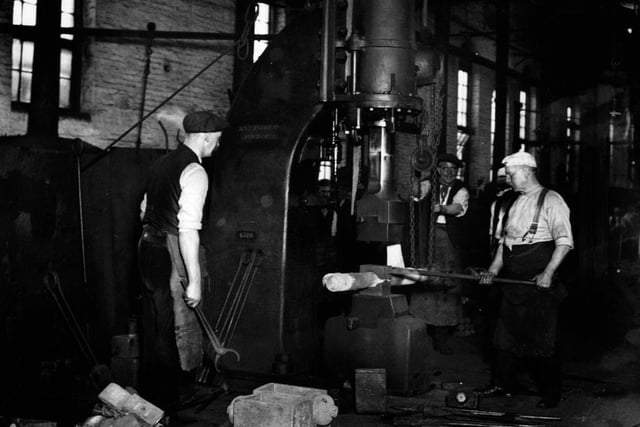 Workers smithing under a steam hammer at the Midland Railway Company's works in Derby around 1926.