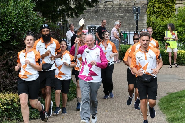 Baton bearer Peter Danson holds the Queen's Baton during the Birmingham 2022 Queen's Baton Relay on a visit to Buxton