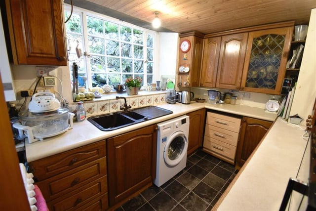Wooden units at base and eye levels offer ample storage space in the kitchen where there is room for a washing machine and an electric cooker.