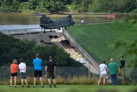 Residents look on as an RAF Chinook helicopter drops sandbags onto the dam wall at Toddbrook reservoir. Photo by Leon Neal/Getty Images