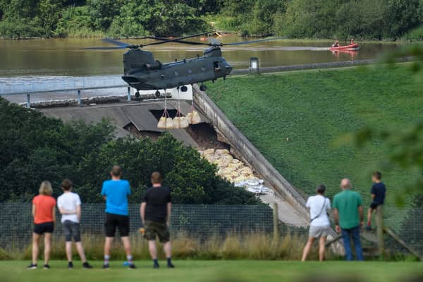 Residents look on as an RAF Chinook helicopter drops sandbags onto the dam wall at Toddbrook reservoir. Photo by Leon Neal/Getty Images