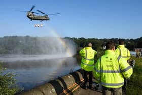 A Chinook helicopter creates a rainbow in the spray as it prepares to drop sandbags onto the dam wall at Toddbrook reservoir. (Photo by Leon Neal/Getty Images)
