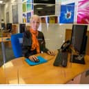 A Hays Travel staff member prepares for reopening behind a perspex screen.