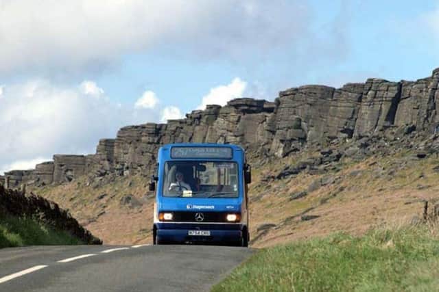 A bus travels along a road below Stanage Edge, near Hathersage in Hope Valley