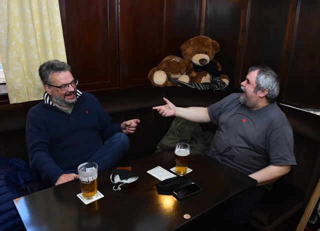 Two customers enjoy a drink at The Queens Head. (Photo by Nathan Stirk/Getty Images)