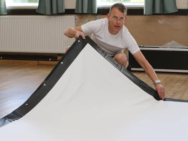 New Mills cinema volunteer Steve Wilson stretching out the newly arrived big screen