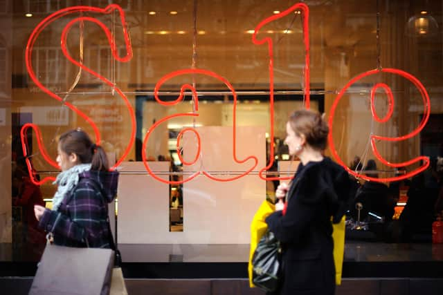 Pedestrians pass a store advertising sales discounts. Picture: Frantzesco Kangaris/Bloomberg via Getty Images.