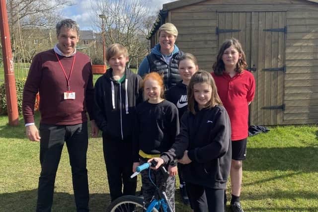 Some of the children at Hayfield Primary School with their headteacher Stefan Papadopoulos and PE Teacher Zoe Shaw, with a bike currently under repair and renewal.