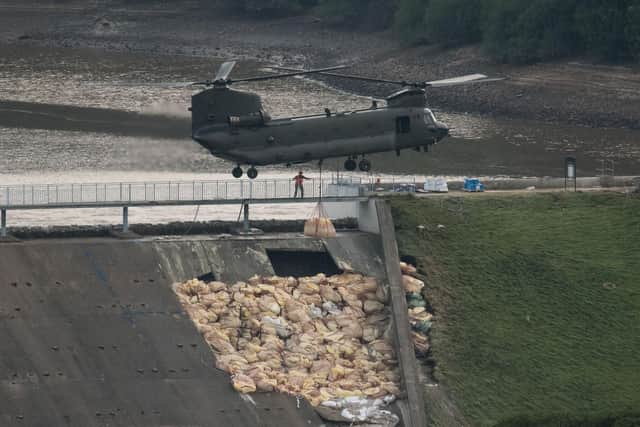 An RAF Chinook helicopter drops bags of aggregate on the damaged section of spillway at Toddbrook Reservoir. Photo - Getty Images