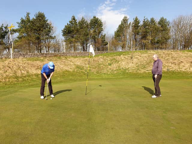 Alan Dickman putting at the fifth hole as Ken Lomas looks on.