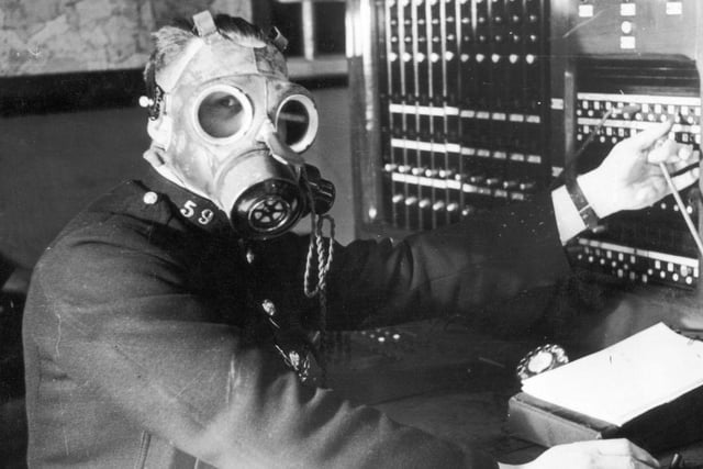 A Chesterfield Borough Police telephone operator tests a gasmask with built in earpiece and microphone. The telephone service is considered one of the most important links in the coordination of ARP operations and must remain operational during air raids, 12th April 1939.