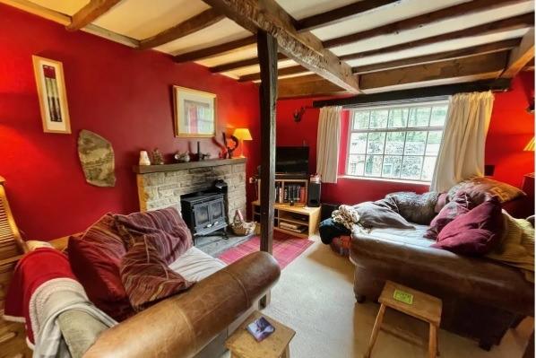 The cosy living room with exposed wooden beams has a cast iron stove sitting in a stone effect fireplace.