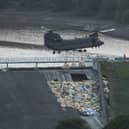 An RAF Chinook helicopter drops bags of aggregate on the damaged section of spillway of the Toddbrook Reservoir dam on August 4, 2019 (photo by OLI SCARFF / AFP).