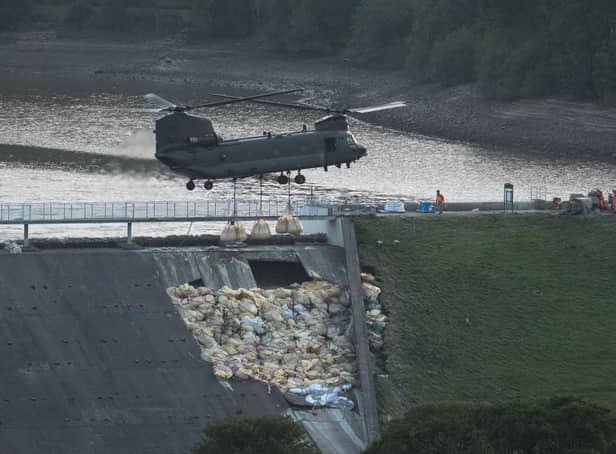 An RAF Chinook helicopter drops bags of aggregate on the damaged section of spillway of the Toddbrook Reservoir dam on August 4, 2019 (photo by OLI SCARFF / AFP).