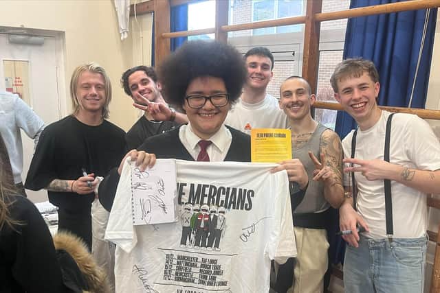 The Mercians and a fan with merch at St Thomas More School.