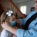 A mother helps her daughter put on a mask (Photo by DESIREE MARTIN / AFP) (Photo by DESIREE MARTIN/AFP via Getty Images)