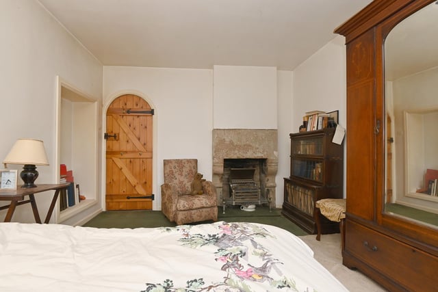 A double bedroom with a fireplace, wall recess feature and arched doorway.