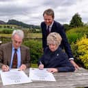 Chief Executive Simon Baker, standing, watches as councillors Tony Ashton and Sybil Ralphs reaffirm the strategic alliance