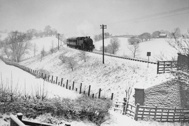 A train passes through a snowy landscape in Derbyshire in January 1936.