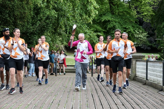 BUXTON, ENGLAND - JULY 11: Batonbearer Peter Danson holds the Queen's Baton during the Birmingham 2022 Queen's Baton Relay on a visit to Buxton, United Kingdom, on July 11, 2022. (Photo by Nick England/Getty Images for Birmingham 2022 Queen's Baton Relay)