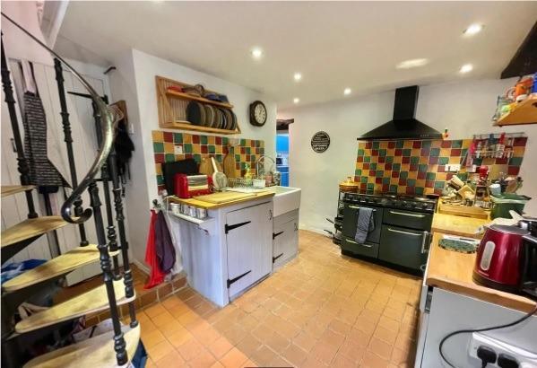 The kitchen is fitted with base mounted units, has tiled splashbacks and a Belfast style sink. There is space for a range style cooker with extractor above and space for a fridge-freezer. A spiral staircase leads to the first floor.