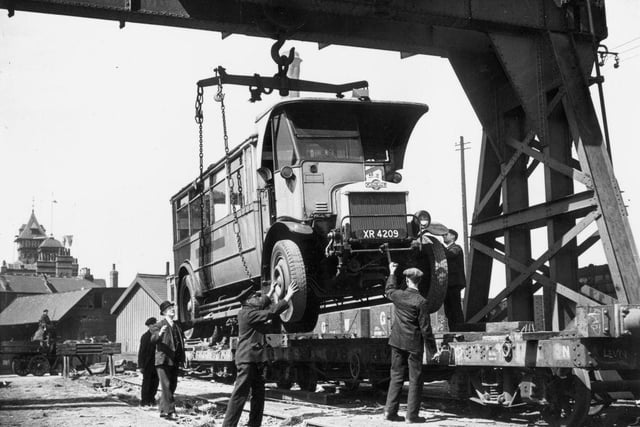 An old double decker bus is loaded onto a railway wagon for its last journey, to Chesterfield, where it will be broken up. The upper deck has been removed to enable it to fit within gauge. Pictured o 26th May 1937.