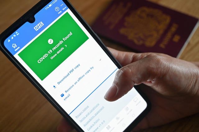 You can find your covid vaccine status on the NHS app. (Photo by JUSTIN TALLIS/AFP via Getty Images)