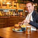 Royal butler eating a burger with a knife and fork